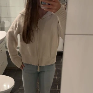 Stickad zip up - Säljer en supermysig vit  hoodie med dragkedja framtill. Den är perfekt för kyliga dagar och har en skön luva. Perfekt för höst och vår!