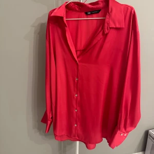 Rosa blus från Zara - Säljer en snygg cerise rosa blus från Zara i storlek XXL. Blusen har långa ärmar och knappar framtill. Perfekt för både vardag och fest! Materialet känns mjukt och lyxigt, och påminner om silke.