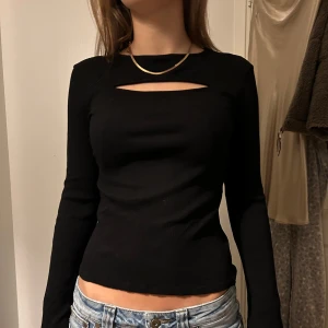 Svart långärmad topp med cut-out - Säljer en snygg svart långärmad topp med cut-out detalj vid halsen. Perfekt för både vardag och fest❣️