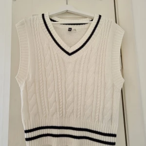 Vit stickad väst med svarta ränder - Säljer en superfin vit stickad väst i storlek XXS men är oversized i storlek (är vanligtvis S-M i övrigt). Den har ett snyggt kabelstickat mönster och svarta ränder vid halsringningen och nederkanten. Perfekt att ha över en skjorta eller t-shirt för en preppy look. Västen är i nyskick och passar perfekt för höst och vår. 🖤🤍