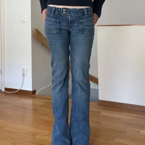 Blå bootcut jeans - Säljer ett par snygga blå bootcut jeans. De är i bra skick och har en klassisk femficksdesign med knappar och dragkedja fram. Perfekta för både vardag och fest!