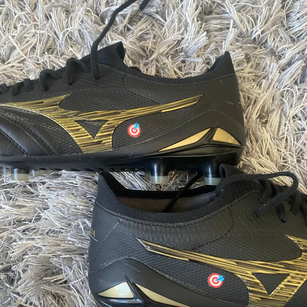 Jag säljer ett par Mizuno Morelia Neo IV black/gold i NYSKICK (använda 2 gånger). Köpta för 3000kr. Pris kan diskuteras. Säljes på grund av att de är för små för mig. På skorna finns även 🎯 tryckt, vilket är en fin detalj. Påsen följer såklart med. . Skor.