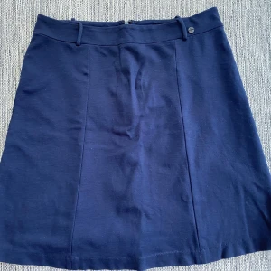 Marinblå kjol i strl L från Marc O’Polo. - Marinblå kjol i strl L från Marc O’Polo.  Sparsamt använd och i fint begagnat skick.  Mått Midjan: ca 44 cm Total längd: ca 54 cm  68% viskos, 29% polyamid och 3% elastan
