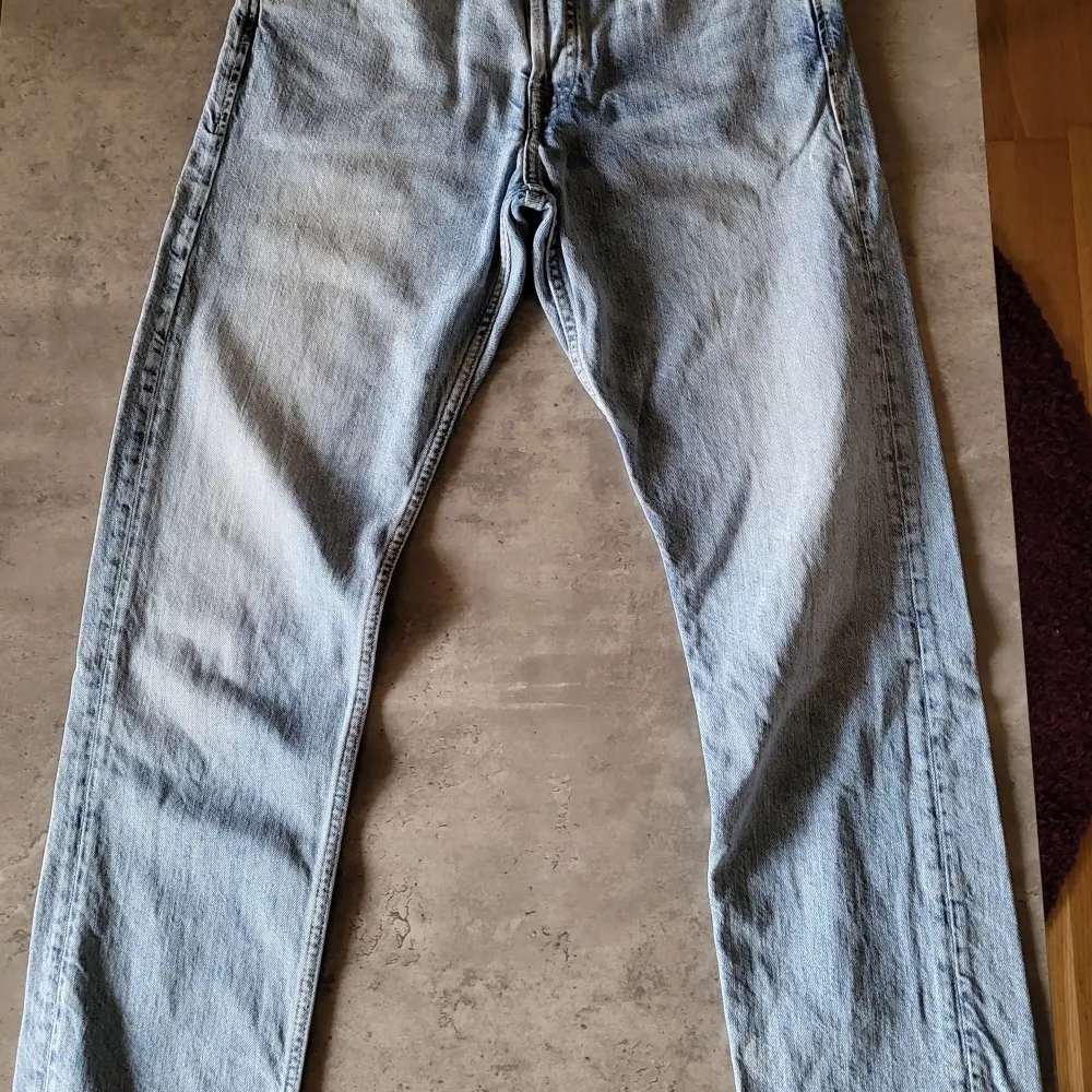 Säljer ett par ljusblå jeans från Jack & Jones. De är i modellen 'Loose/Chris' och har en avslappnad passform. Jeansen är tillverkade av bomull och har en klassisk femficksdesign med dragkedja och knapp. Perfekta för en casual look!. Jeans & Byxor.