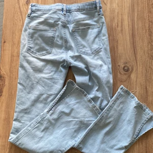 Ljusblå jeansbyxor - Säljer ett par ljusblå jeansbyxor i storlek 164. Byxorna har en hög midja och en straight passform. De är tillverkade av bomull och har en klassisk femficksdesign med dragkedja och knapp framtill. Perfekta för vår och sommar!