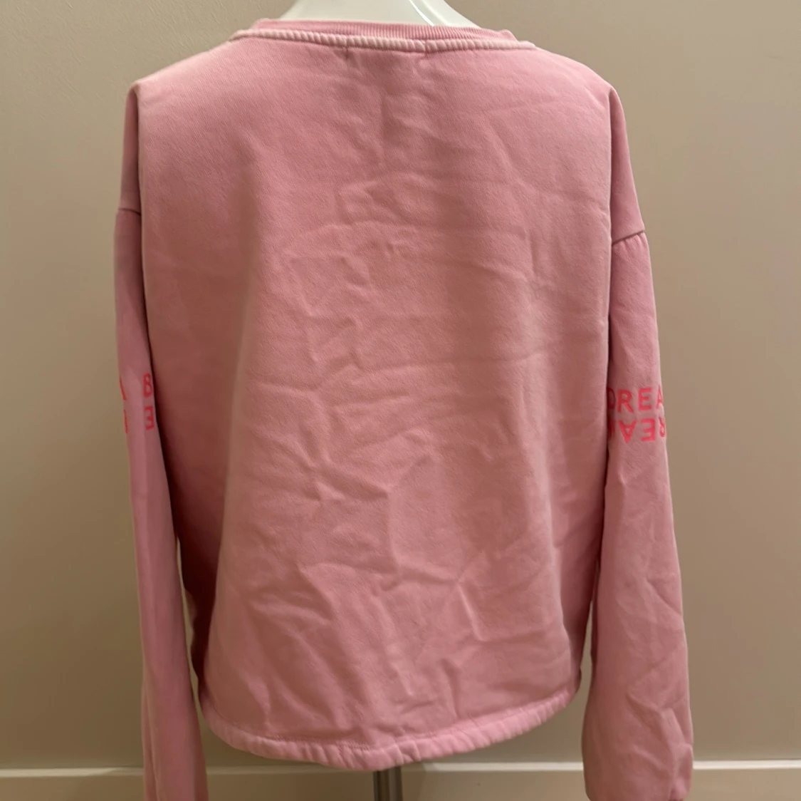 En ljus rosa sweatshirt med rosa och vit text på - 90