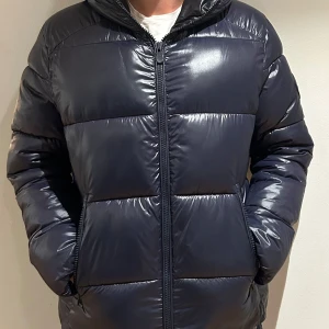 Mörkblå pufferjacka med huva - Säljer en mörkblå pufferjacka i mycket bra skick. Använd en halv vinter. Storlek L