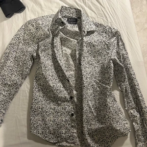 Vit blommig skjorta från Dressmann - Säljer en snygg vit skjorta med blommigt mönster från Dressmann. Skjortan är i slim fit och har långa ärmar. Perfekt för både vardag och fest! Den är i mycket bra skick och gjord av ett stretchigt material för extra komfort.