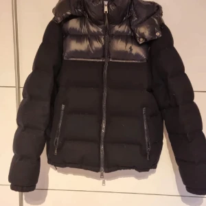 Svart pufferjacka från Polo Ralph Lauren - Säljer en snygg svart pufferjacka från Polo Ralph Lauren i storlek L. Jackan har en glansig finish upptill och är perfekt för kalla dagar. Säljer den då den inte passar mig så bra. Perfekt för vintern och hösten! 🖤
