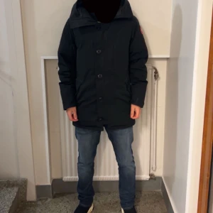  Canada Goose jacka  - Hej ! Säljer en svart parkajacka från Canada Goose i mycket bra skick. Jackan har en klassisk design med knappar och en broderad logga på ärmen. Perfekt för kalla vinterdagar med sin varma och skyddande stil. Passar både till vardags och mer formella tillfällen. Kom gärna med prisförslag jackan är självklart äkta