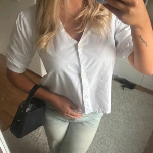 Vit kortärmad blus - Säljer en  vit blus med korta ärmar och knappar framtill. Perfekt för både vardag och festliga tillfällen. 