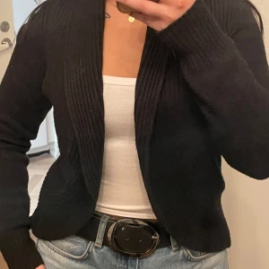 Svart kofta - Säljer en stilren svart kofta i bra skick. Den är perfekt för både vardag och lite finare tillfällen. Koftan har långa ärmar och en ribbad design som ger en snygg passform. Passar perfekt över en topp eller blus. Perfekt för höst och vinter!