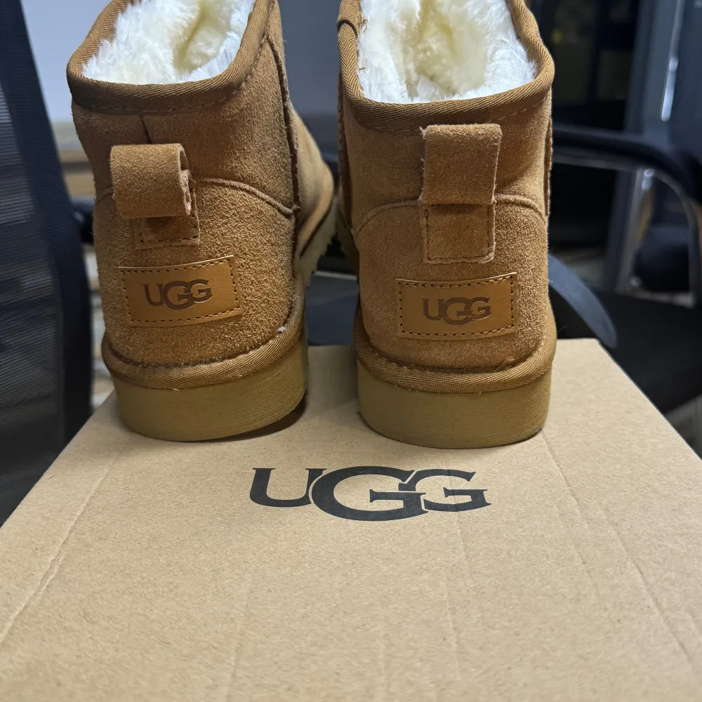 Säljer ett par klassiska bruna UGG boots i mjuk mocka. De har en fluffig insida som håller fötterna varma och sköna under kalla dagar. Perfekta för höst och vinter! De är i nytt skick och kommer i originalkartong.. Skor.