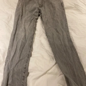 Grå jeansbyxor - Säljer ett par grå jeans från Carlings i bra skick. De har en klassisk straight passform och är perfekta för vardagsbruk. Byxorna har en midwaist och är tillverkade i slitstarkt denim. Modellen på bilden är 166 cm lång.