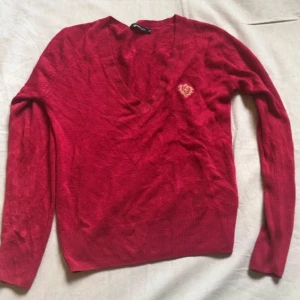 Röd V-ringad tröja från Cool - Säljer en snygg röd V-ringad tröja från Gina Tricot i storlek XS. Tröjan är gjord av 100% akryl och har en broderad detalj på bröstet. Perfekt för höst och vinter med sina långa ärmar och ribbade kanter. Passar både till vardags och fest! 🍂❤️