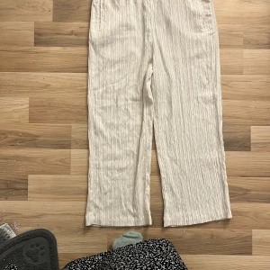 Beige byxor från Lindex - Säljer ett par snygga beige byxor från Lindex i storlek 44. De har en loose passform och är perfekta för vår och sommar. Byxorna är tillverkade i ett lätt och bekvämt material, vilket gör dem idealiska för varma dagar. 