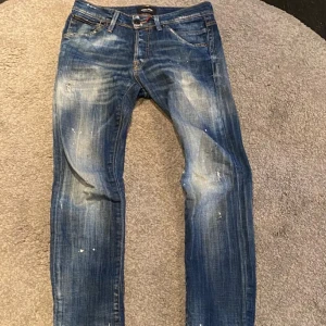 Limited editon jacka and Jones jeans, gleen slim L32 - Snygga blå jeans från Jack & Jones med en sliten look och ljusa tvättade detaljer. De har en klassisk femficksdesign och knappgylf. Perfekta för en avslappnad stil. L32/W28