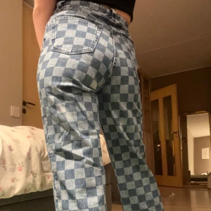 Rutiga jeans - Snygga blå jeans med rutigt mönster. Byxorna har en rak passform och är tillverkade av 100% bomull. Perfekta för en avslappnad stil.