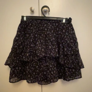 Volang kjol - Jättefin kort kjol med volanger och gulligt blommtryck! Den har en svart underkjol. Säljer samma i svart-vitt
