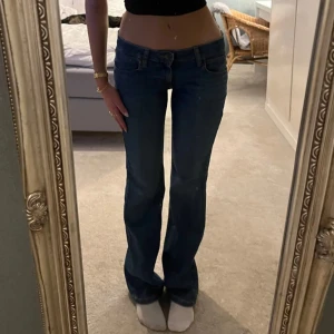 Blå bootcut jeans från Lee - Snygga blå bootcut jeans från Lee med klassisk femficksdesign. De har en lågmidjad passform och är perfekta för en avslappnad stil. Säljer dem för att jag köpte dem på Plick men dem inte passade. Storlek w26 och passar i längden 167cm eller längre.