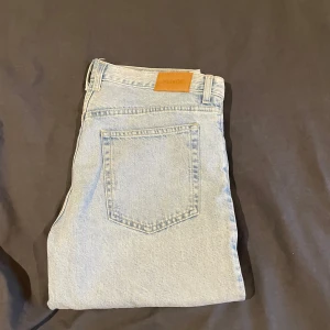 Ljusblå jeans från Weekday - Snygga ljusblå jeans från Weekday med klassisk femficksdesign och knappgylf. Perfekta för en avslappnad stil. Märkeslapp i brunt läder baktill. Få använda byxor som är i ett bra skick och som sitter bra. Barrel modell på byxorna så dom är inte stora men inte slim fit heller, nått där mitt emellan. Storlek är 31/32. Köpta på weekday för 799. 