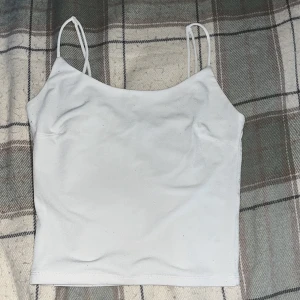 Vit linnetopp från BikBok - Säljer en stilren vit linnetopp från BikBok i storlek XS. Toppen har smala axelband och en enkel design som passar perfekt till sommaren. Perfekt för en avslappnad look!