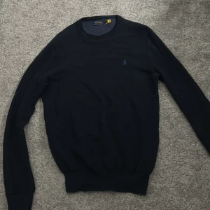 Tröja från Polo Ralph Lauren - Säljer en stilren mörkblå tröja från Polo Ralph Lauren med det klassiska logotypbroderiet på bröstet. Tröjan har långa ärmar och en rund halsringning. Storlek S sitter stort så passar nog bättre som M