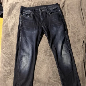 Mörkblå jeansbyxor från G-star - Snygga mörkblå jeansbyxor med en klassisk femficksdesign. De har en smal passform och är perfekta för en stilren look. Byxorna har en knapp och dragkedja framtill. Storlek 30:30
