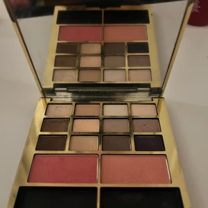 Ögonskuggspalett från Estée Lauder - Elegant ögonskuggspalett från Estée Lauder med 12 nyanser och 2 rouge. Paletten har en lyxig guldig design och inkluderar färger som rosa, nude och metalliska toner. Perfekt för att skapa både vardagliga och dramatiska looks.