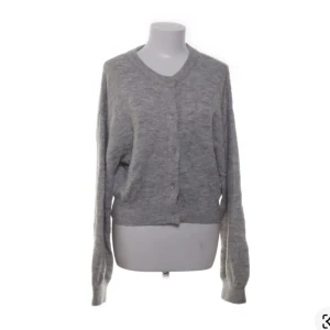 Grå kofta från H&M Divided - Säljer en stilren grå kofta från H&M Divided. Koftan har långa ärmar och knappar framtill. Perfekt för lager-på-lager under kyligare dagar. Materialet är en blandning av akryl, polyamid, polyester och elastan.