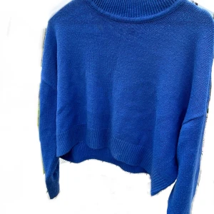 Blå stickad från H&M Divided - Säljer en snygg blå stickad tröja från H&M Divided. Den har ribbade detaljer vid ärmslut och nederkant. Passar perfekt till jeans eller kjol för en stilren look.