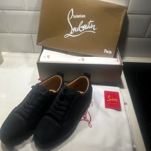 Marinblå sneakers från Christian Louboutin - Snygga mörkblå sneakers från Christian Louboutin med den ikoniska röda sulan. Skorna har snörning och är tillverkade i mocka. Knappt använda, syns bara under skon på sulan att de är använda. :-) 