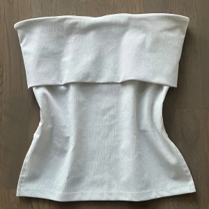 Vit topp - Säljer en stilren vit tubtopp i ett mjukt och stretchigt material med slits på sidorna. Är i mycket bra skick🫶