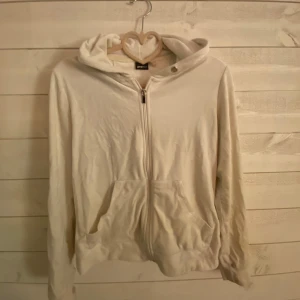 Vit hoodie från Gina Tricot - Säljer en vit hoodie från Gina Tricot i storlek XS. Den har en dragkedja framtill och en mysig huva. Tyvärr några små fläckar på axeln/ armen som syns på sista bilden. Kan säkert gå bort i tvätten. 