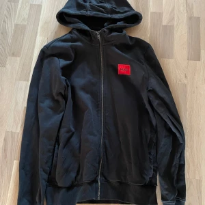 HUGO Zip Hoodie M - Säljer en svart HUGO Zip hoodie i storlek M. Sjukt clean tröja som är sparsamt använd. Bara att höra av sig vid intresse! Mvh