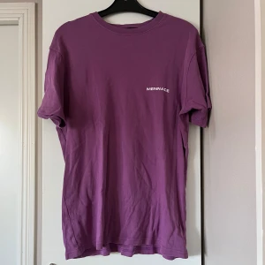 Lila t-shirt från Mennace - Säljer en snygg lila t-shirt från Mennace med tryck både fram och bak. Den har en klassisk rund hals och korta ärmar. 