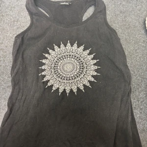 Svart linne från Natura med mandalamönster - Snyggt svart linne från Natura med ett detaljerat vitt mandalamönster på framsidan. Är storlek L men skulle säga att den är som en xs