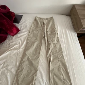 Beige cargobyxor från Zara - Snygga beige cargobyxor från Zara med flera praktiska fickor och dragkedja. Byxorna har en avslappnad passform och är perfekta för en casual look.