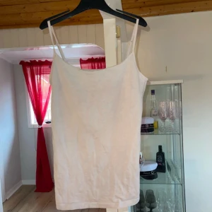 Beige linnetopp från Basic You - Säljer en enkel och stilren beige linnetopp från Basic You. Toppen har smala axelband och är tillverkad i ett mjukt bomullsmaterial. Perfekt för varma dagar eller som lager under andra plagg. Har en liten fläck som man ser på sista bilden men går säkert bort efter en tvätt