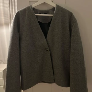 Grå kavaj från BikBok - Snygg grå kavaj från BikBok i storlek S. Den har en stilren design med en enkel knapp framtill och långa ärmar. Perfekt för en chic och minimalistisk look.