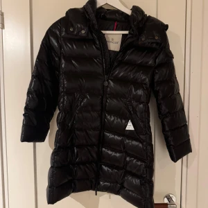 Svart dunjacka från Moncler - En snygg moncler jacka i modellen moka. Den är i bra sick och inga synliga skador. Jackan är i storelk 8-10 år. Tveka inte på att höra av dig vid frågor eller funderingar.