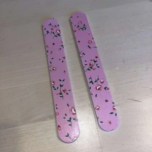 Nagelfilar - Två rosa nagelfilar med ett sött blommönster. Perfekta för att hålla naglarna i toppskick med stil. Lätta att använda och praktiska att ha med sig i väskan. Helt nya! Priset är för båda!