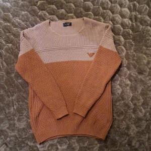 Beige och brun stickad tröja från Armani Jeans - Säljer en snygg stickad tröja från Armani Jeans i beige och brun. Tröjan har ett diskret märke på bröstet och är perfekt för kyligare dagar. Den har en rund hals och långa ärmar med ribbade muddar. Liten defekt på etiketten men annars i toppskick. 
