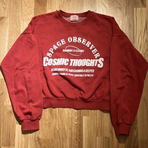 Röd sweatshirt från Pull&Bear - Säljer en cool röd sweatshirt från Pull&Bear med trycket 'Space Observer Cosmic Thoughts' i vitt på framsidan. Tröjan har långa ärmar och en klassisk rund halsringning. Perfekt för en avslappnad stil.