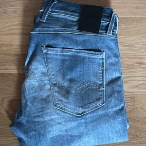 Blå jeans från Replay - Säljer dessa riktigt snygga Replay anbass jeans i storlek 30/32 dessa har snygga slitningar såsom hål på högra benet vilket gör byxorna riktigt snygga