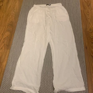 Vita linnebyxor med fickor - Säljer ett par vita stilrena linnebyxor med snörning i midjan. Byxorna har en avslappnad passform och är perfekta för varma dagar. De har två fickor där fram och en ficka där bak. Linnebyxorna finns också på mitt vinted konto som heter tilde.karlsson. 