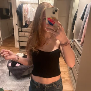 Svart ribbad tubtopp - Säljer en stilren svart ribbad tubtopp. Perfekt för en trendig look med en croppad passform. Enkel att matcha med olika outfits.