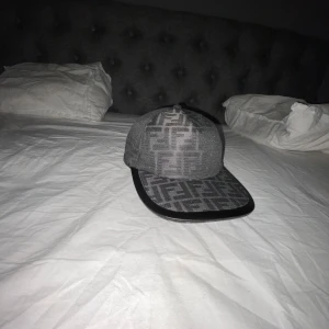 Svart keps från Fendi - Snygg grå keps från Fendi.Den är äkta men har tyvärr gett bort kvitto o allt annat till en vän.Har bara testat kepsen ett par gånger så de är inga skador eller nåt på den.Den paketeras me papper så de inte blir några skador medans de fraktas.