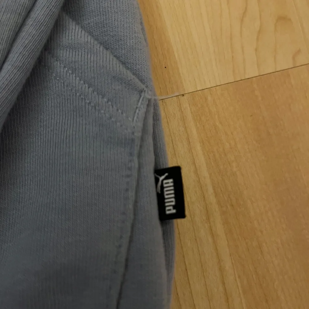 Säljer en stilren blå hoodie från Puma med dragkedja och huva. Tröjan har långa ärmar och en praktisk ficka framtill. Perfekt för en avslappnad look.. Neuletakit & Villapaidat.