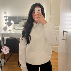 Vit hoodie från bikbok - Säljer en stilren vit hoodie med känguruficka och justerbar huva. Perfekt för en avslappnad look. Den har långa ärmar och en mjuk insida för extra komfort. Passar bra till både jeans och mjukisbyxor. Har missfärgning på ärmen.
